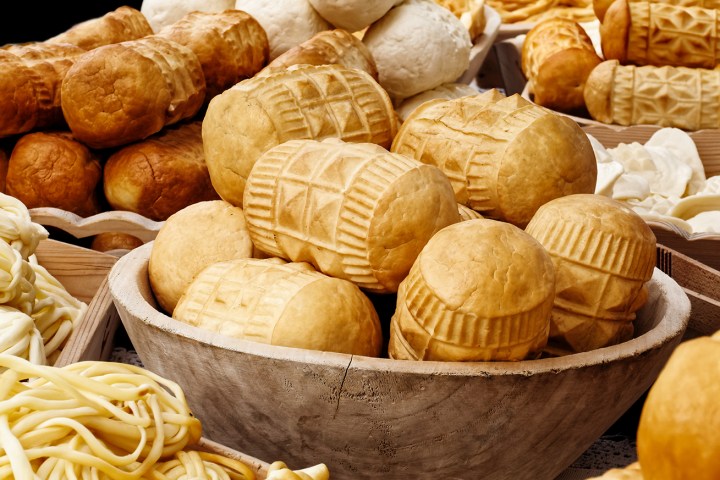 Many kinds of oscypek smoked cheese next to korbacik cheese on black background.