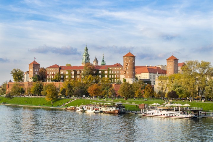 a large body of water with Wawel Castle in the background
