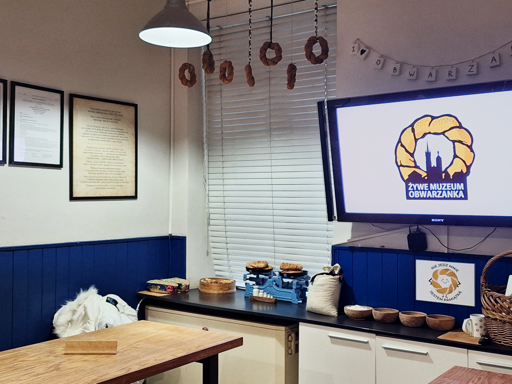 Exhibit room with bagels, framed texts, screen, and a banner.