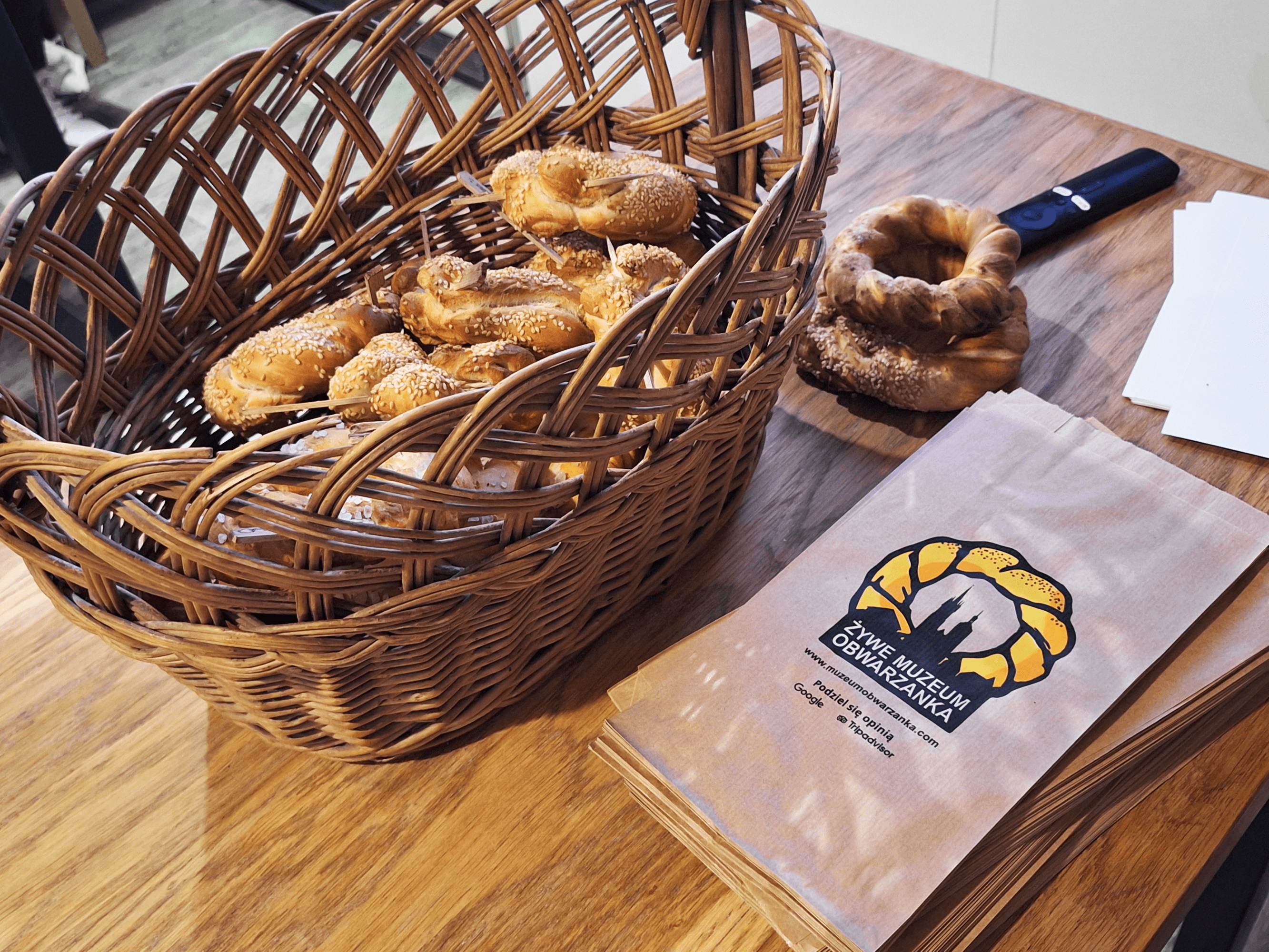 Basket with pastries next to a paper bag on a wooden table.
