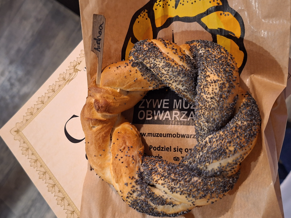 Twisted poppy seed bread on a paper bag with partial logo visible.