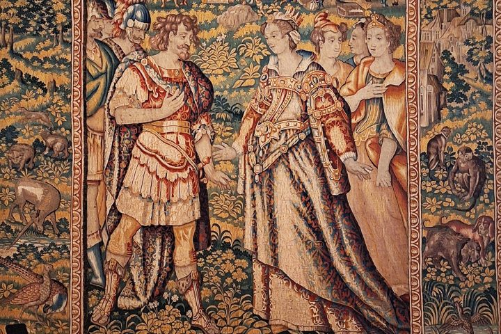 Intricate tapestry with people in historic clothing, surrounded by nature and animals.
