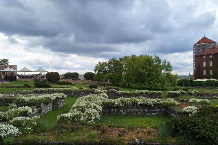 Historic garden with clouded sky and old building in background.