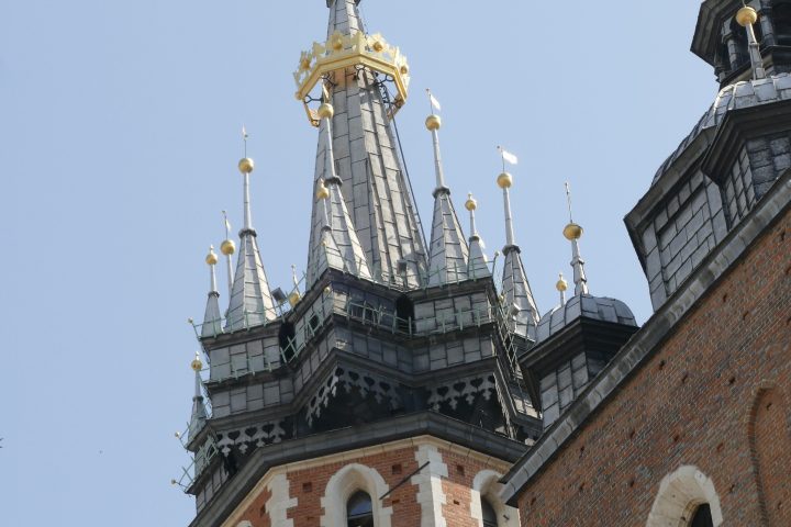 Tall, ornate Gothic church tower with spires against a clear blue sky.