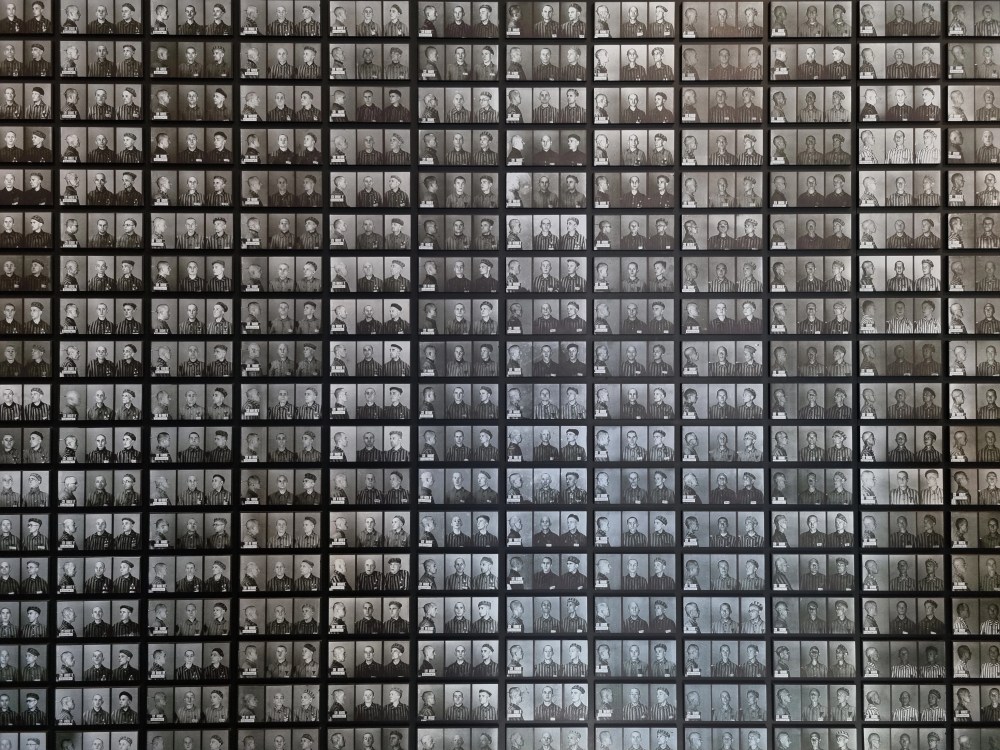 Wall of numerous black and white portrait photos arranged in a grid pattern.