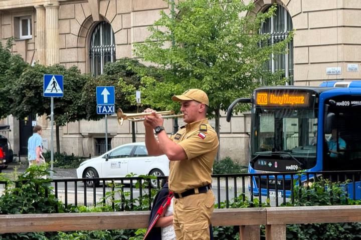 Person in uniform takes a photo near a bus stop in a city setting.