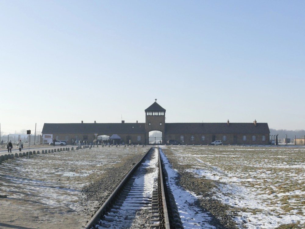 Snowy railway leading to brick gatehouse under clear sky.