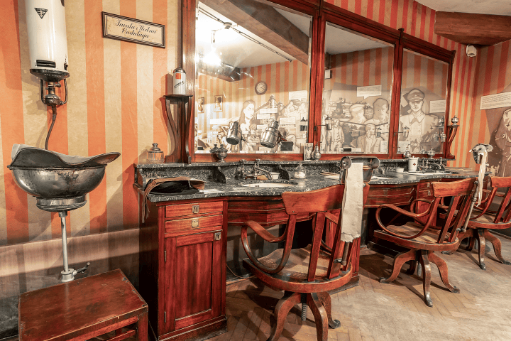 Vintage barbershop with wooden chairs, mirrors, and striped walls.