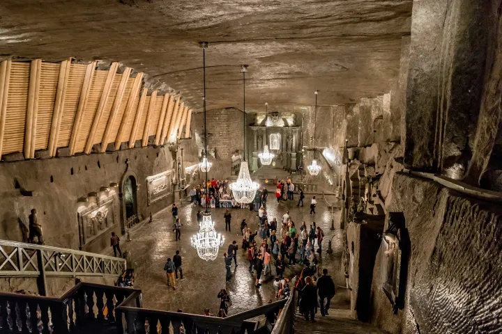 Tourists exploring a large underground chamber with chandeliers and rock walls.