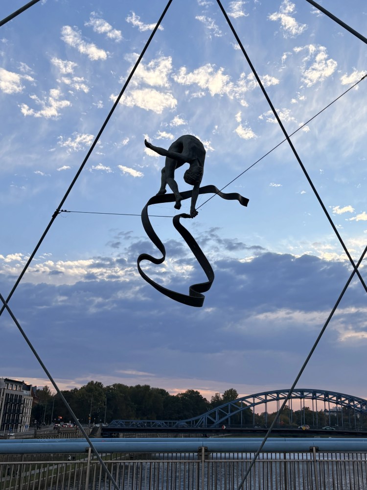 Silhouette of a person on a slackline over a river at sunset.