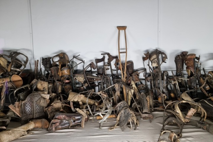 Collection of vintage prosthetics and crutches against a white wall.