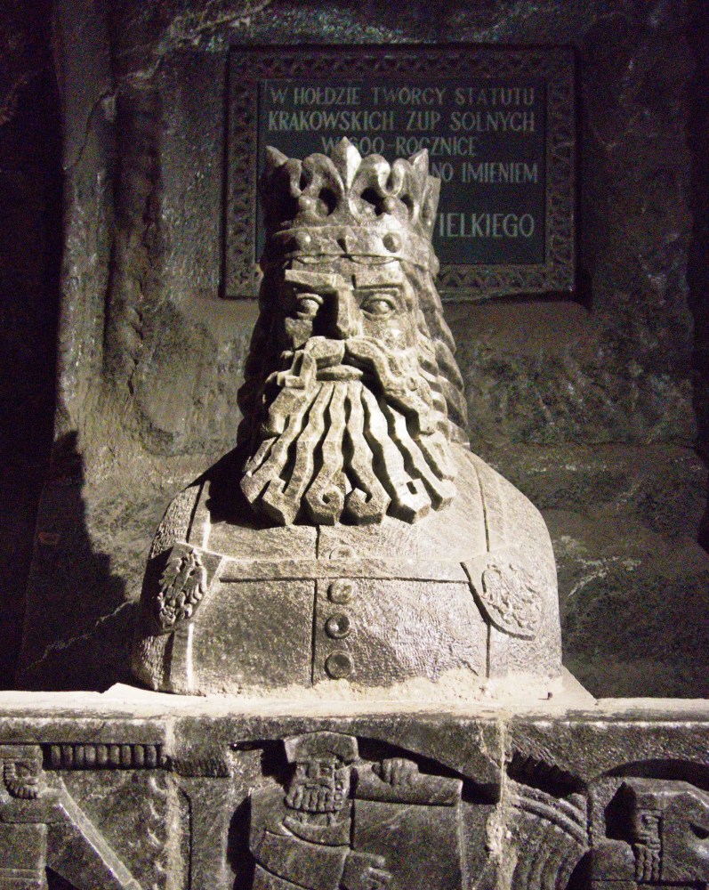 Stone statue of a crowned bearded figure in a dimly lit room.