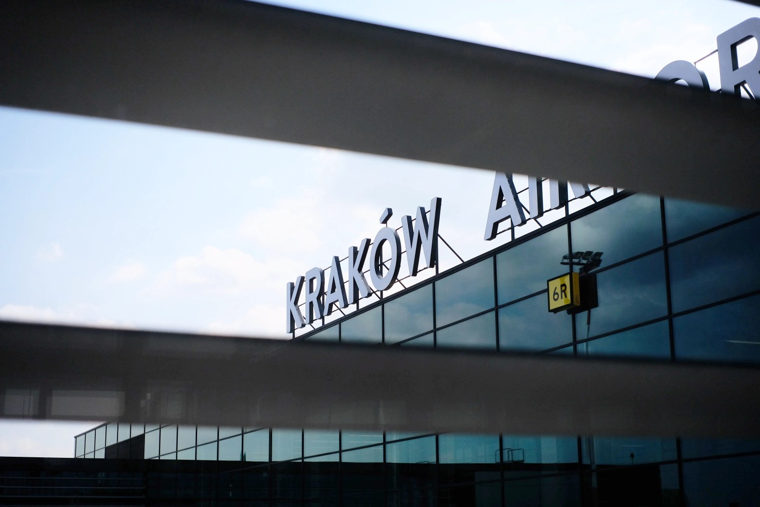Krakow Airport sign viewed through slatted blinds.