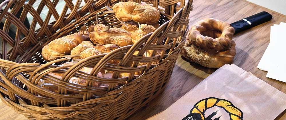Basket of pretzels and a paper bag on a wooden table.