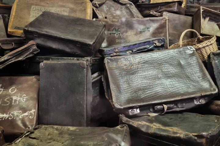 Pile of old, weathered suitcases and baskets stacked against a white background.