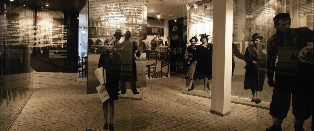 Museum exhibit with historical figures on glass panels and text above.